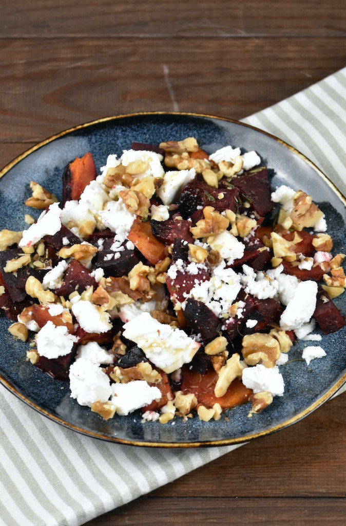 Ofenkürbis mit Schafskäse auf dunklem Teller.