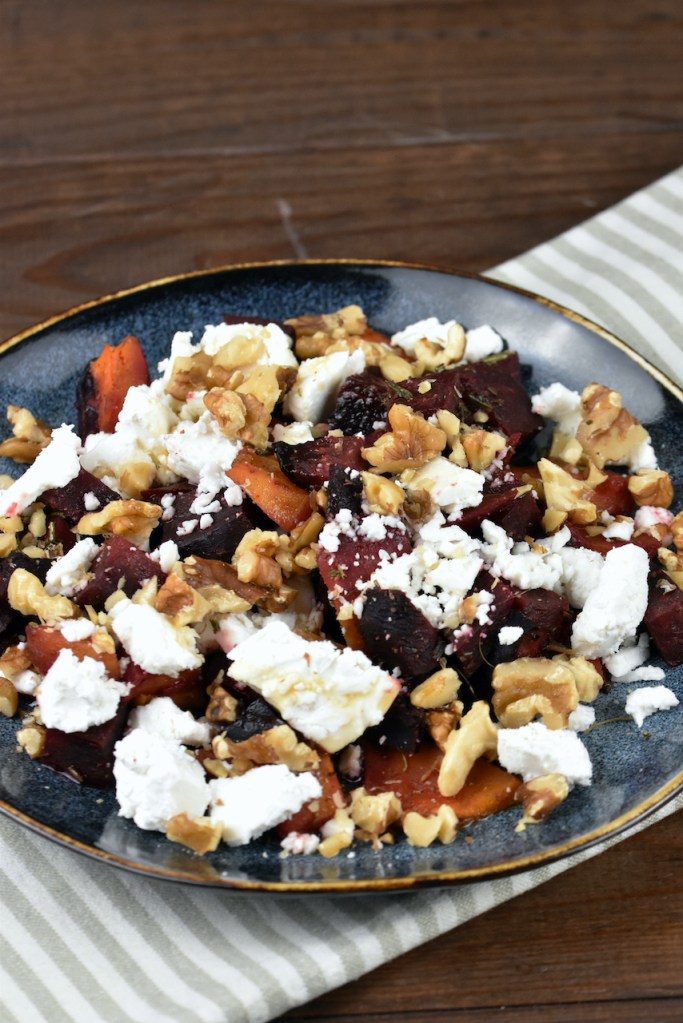 Ofenkürbis mit Schafskäse auf dunklem Teller.