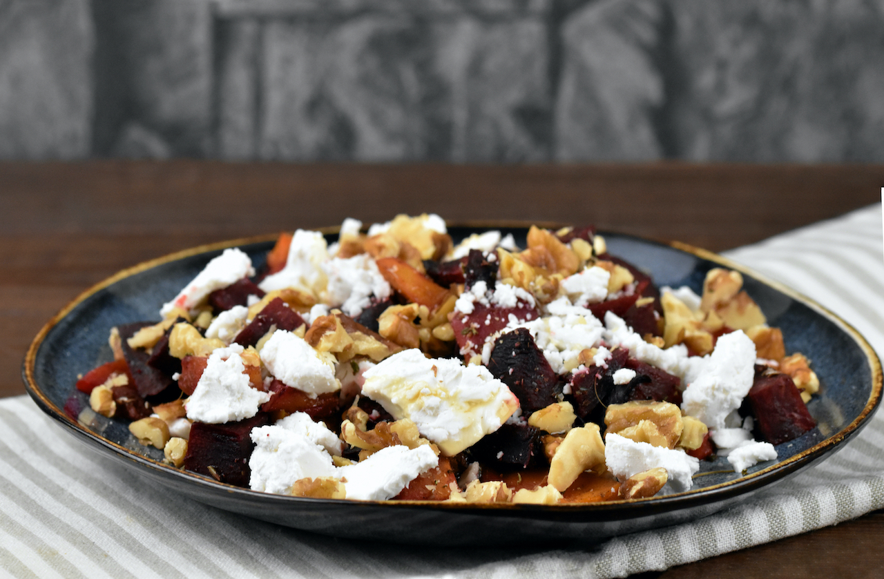 Ofenkürbis mit Schafskäse auf dunklem Teller.