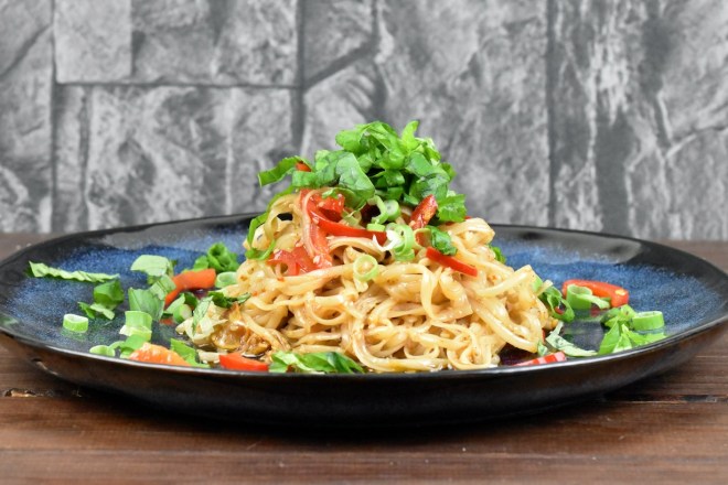 Chilinudeln mit knusprigem Sesam auf blauem Teller