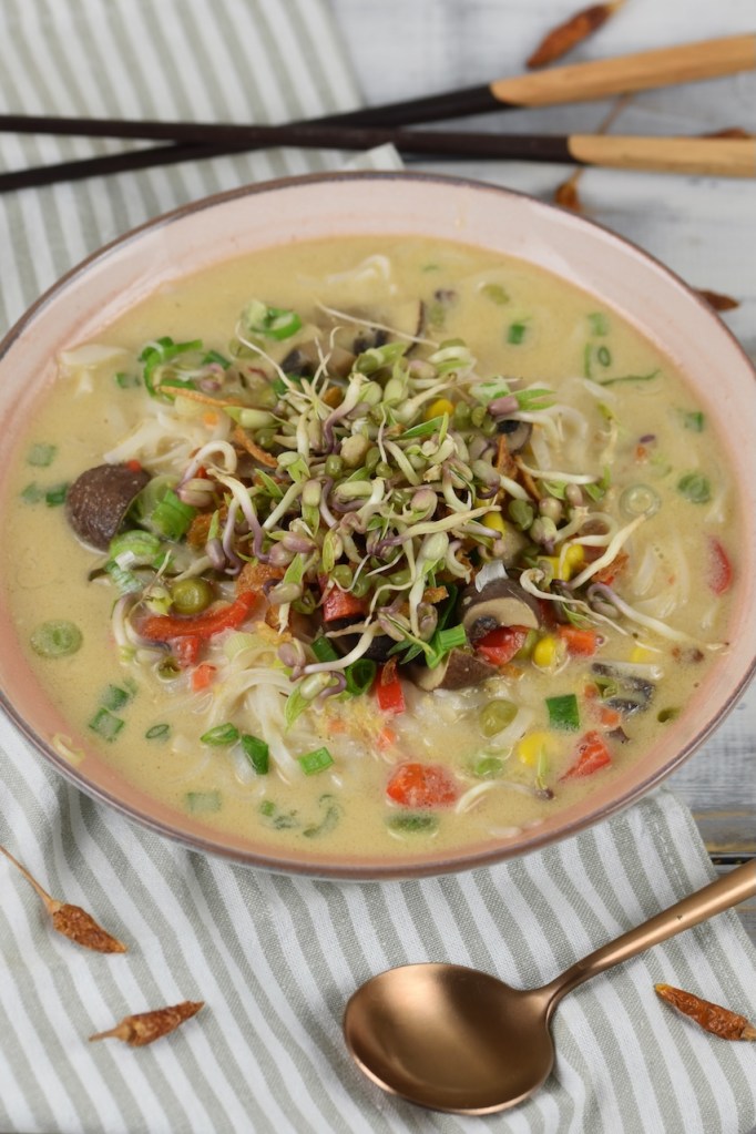 Thai-Suppe mit Kokosmilch und Zitronengras in heller Schale.