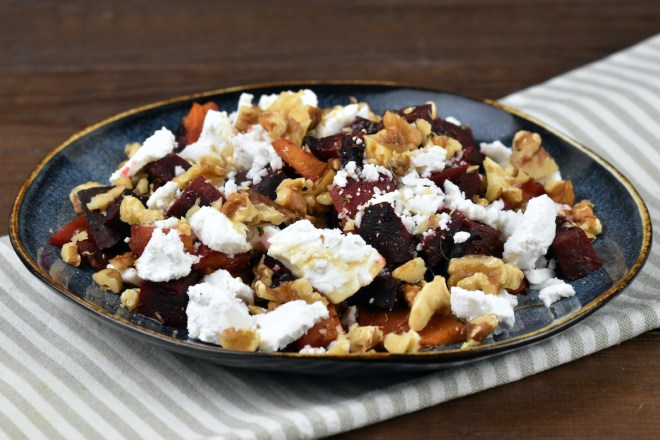 Ofenkürbis mit Schafskäse auf dunklem Teller.