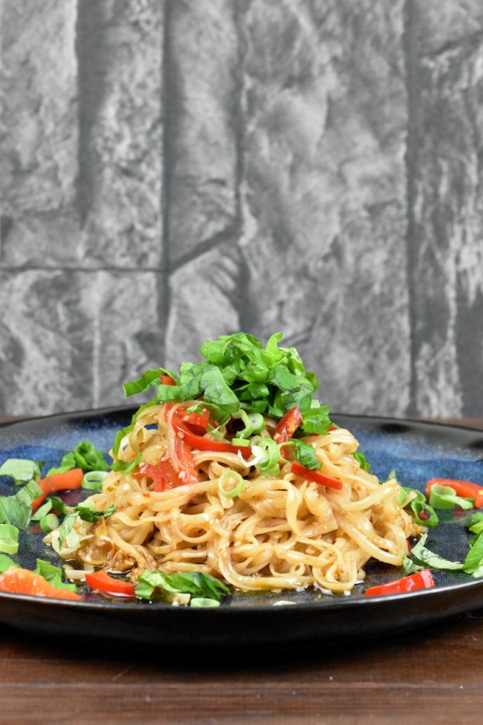 Chilinudeln mit knusprigem Sesam auf blauem Teller