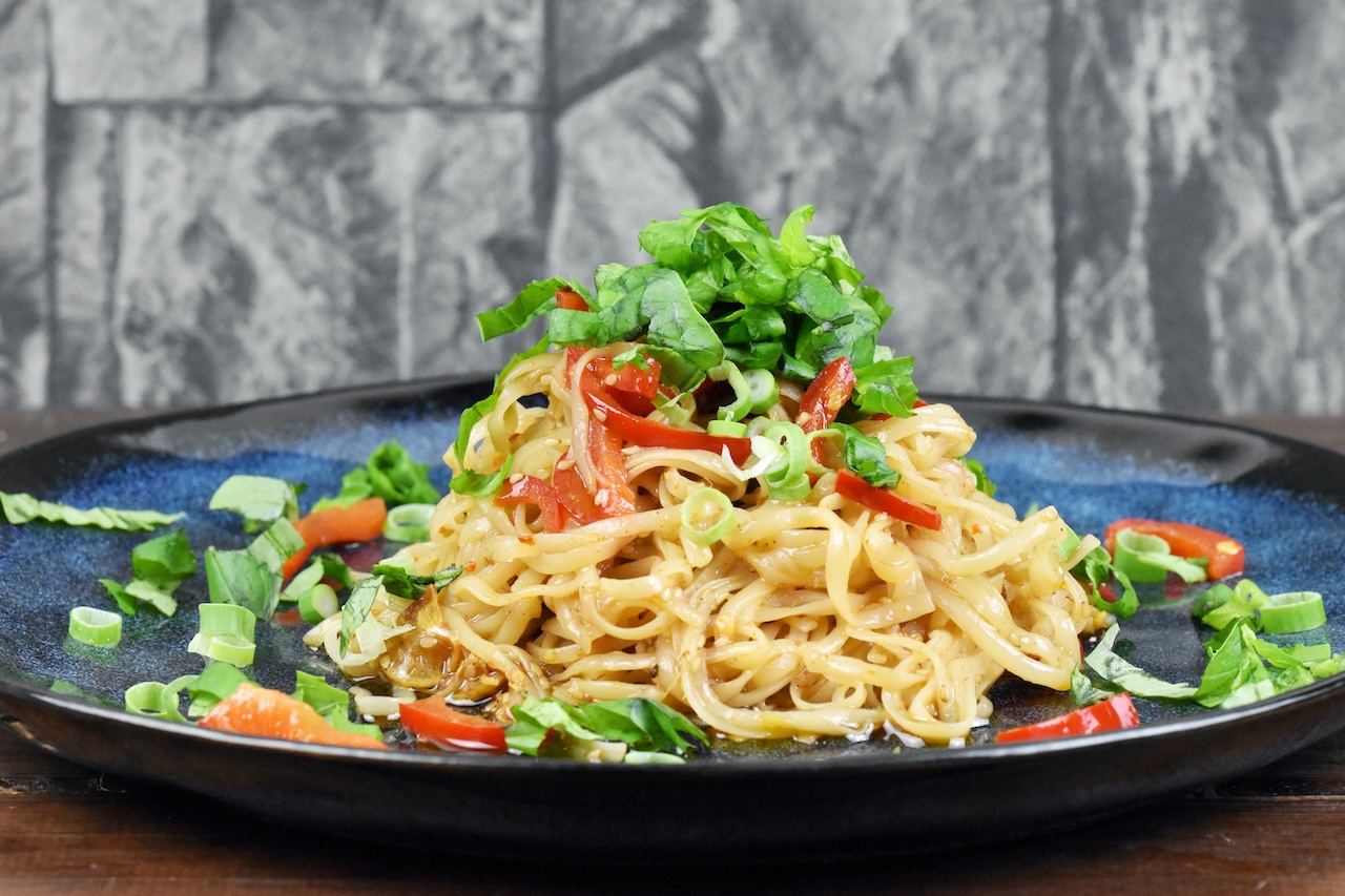 Chilinudeln mit knusprigem Sesam auf blauem Teller