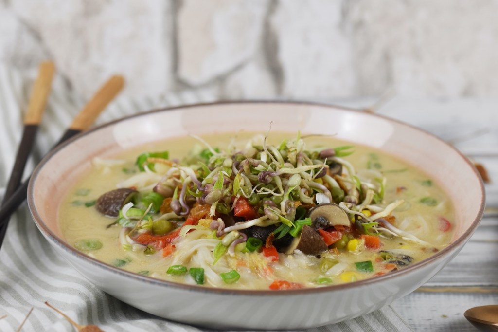 Thai-Suppe mit Kokosmilch und Zitronengras in heller Schale.